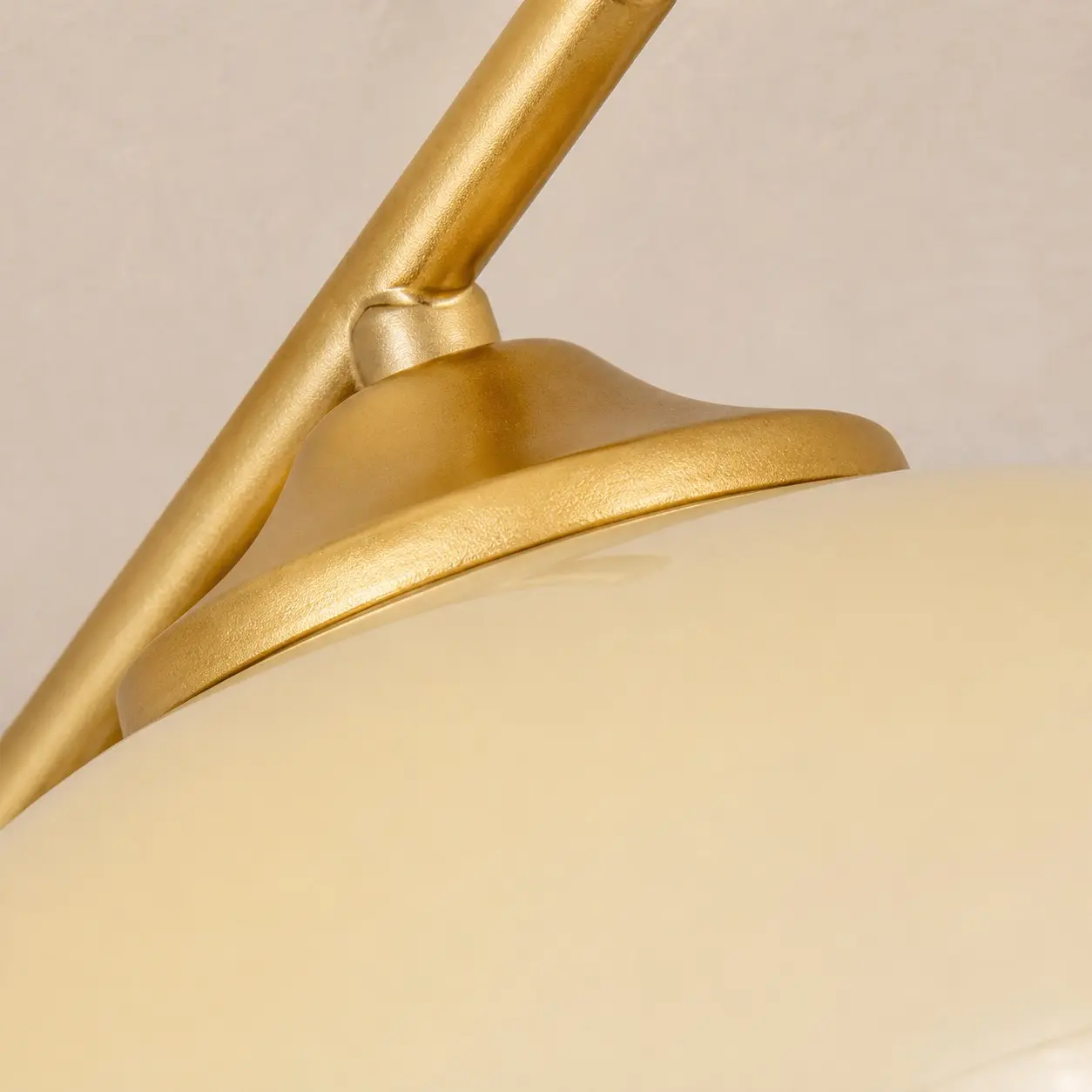 Close-up of the gold lamp arm and white glass shade